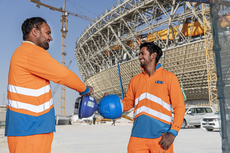 عمال يقفون خارج استاد لوسيل – كأس العالم FIFA قطر ٢٠٢٢™