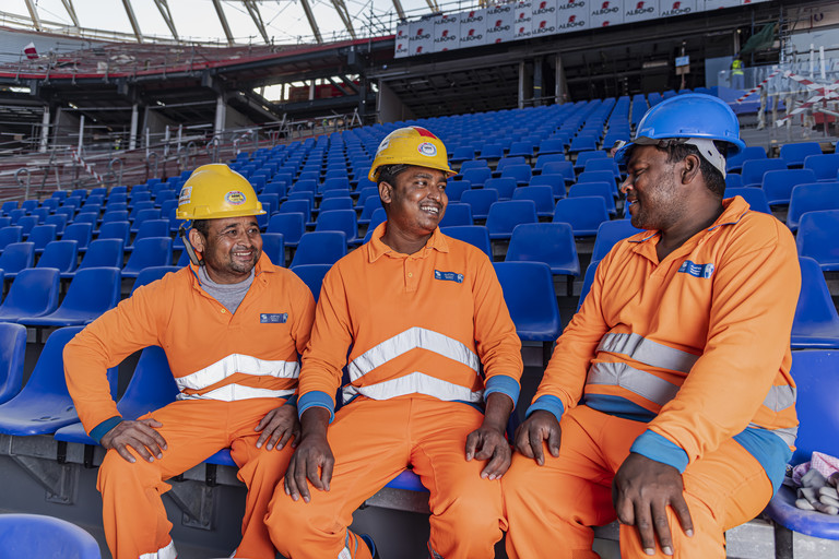 عمال يجلسون داخل استاد راس أبو عبود – أحد مواقع المشاريع التابعة لكأس العالم FIFA قطر ٢٠٢٢™