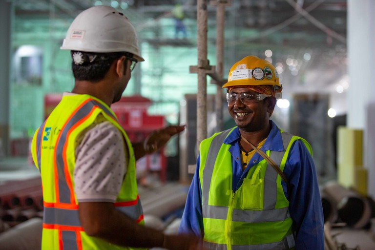 عامل يتحاور مع مسؤول رعاية العمال بأحد مواقع البناء التابعة لكأس العالم FIFA قطر ٢٠٢٢™